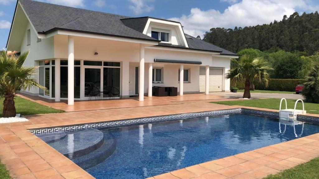 una casa con piscina frente a una casa en Villa LA PERLA con piscina privada en Parbayón
