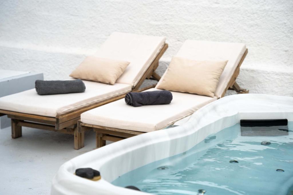 two chaise lounges and a swimming pool with a hot tub at Sunrise Villa Santorini in Vourvoulos