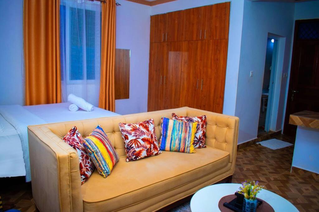 een woonkamer met een bank met kussens bij Cambric Luxe Studio Apartment in Kilifi
