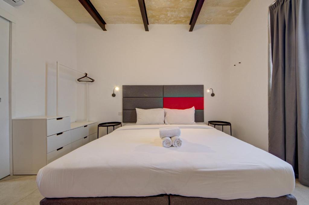 a bedroom with a large white bed with two towels on it at Casa Domenico 6 in Valletta