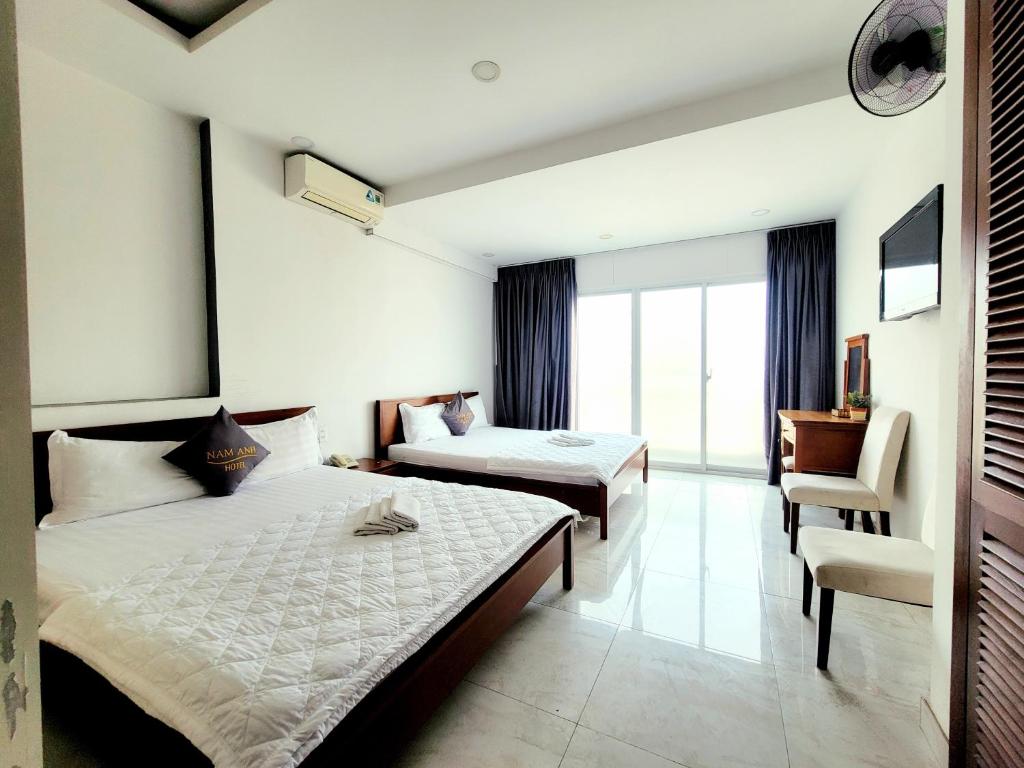 een hotelkamer met 2 bedden en een stoel bij Nam Anh 2 Hotel in Ho Chi Minh-stad
