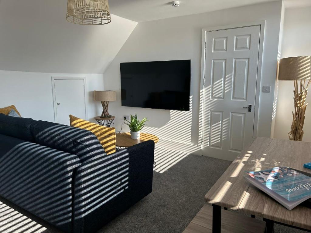 a living room with a couch and a tv at Weymouth Harbour Luxury Apartment in Weymouth