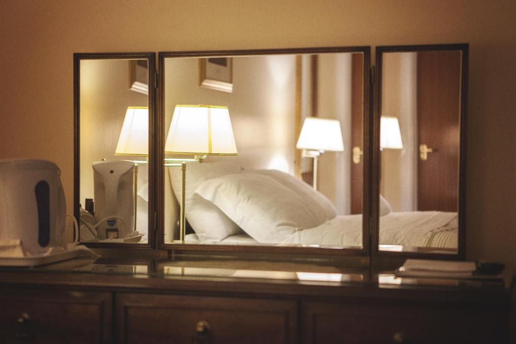 a mirror on a dresser next to a bed at The Derg Arms B&B in Castlederg