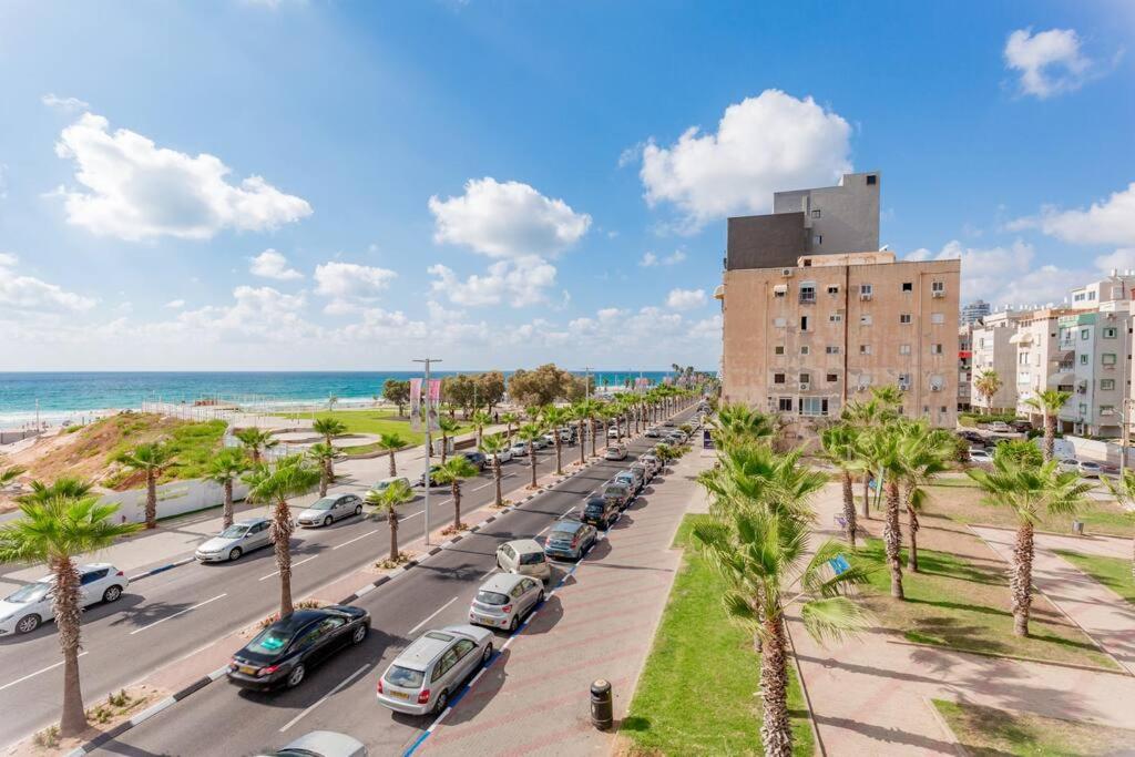 een straat met geparkeerde auto's en een gebouw en de oceaan bij Rooftop Tel aviv Studio in Bat Yam