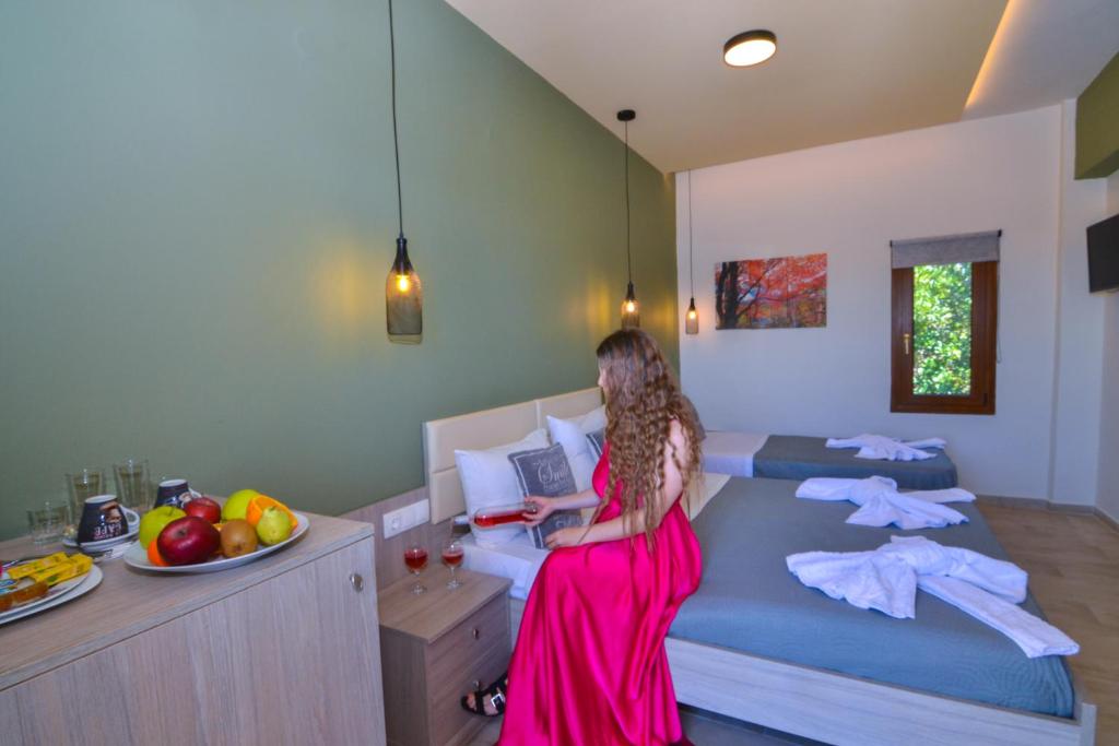 a girl in a pink dress sitting on a bed with a laptop at Elafonisi Paradise with Parking, WiFi, - Walking Distance to the Beach in Elafonisi