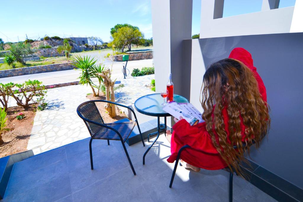 a woman sitting at a table on a balcony at Elafonisi Paradise with Parking, WiFi, - Walking Distance to the Beach in Elafonisi