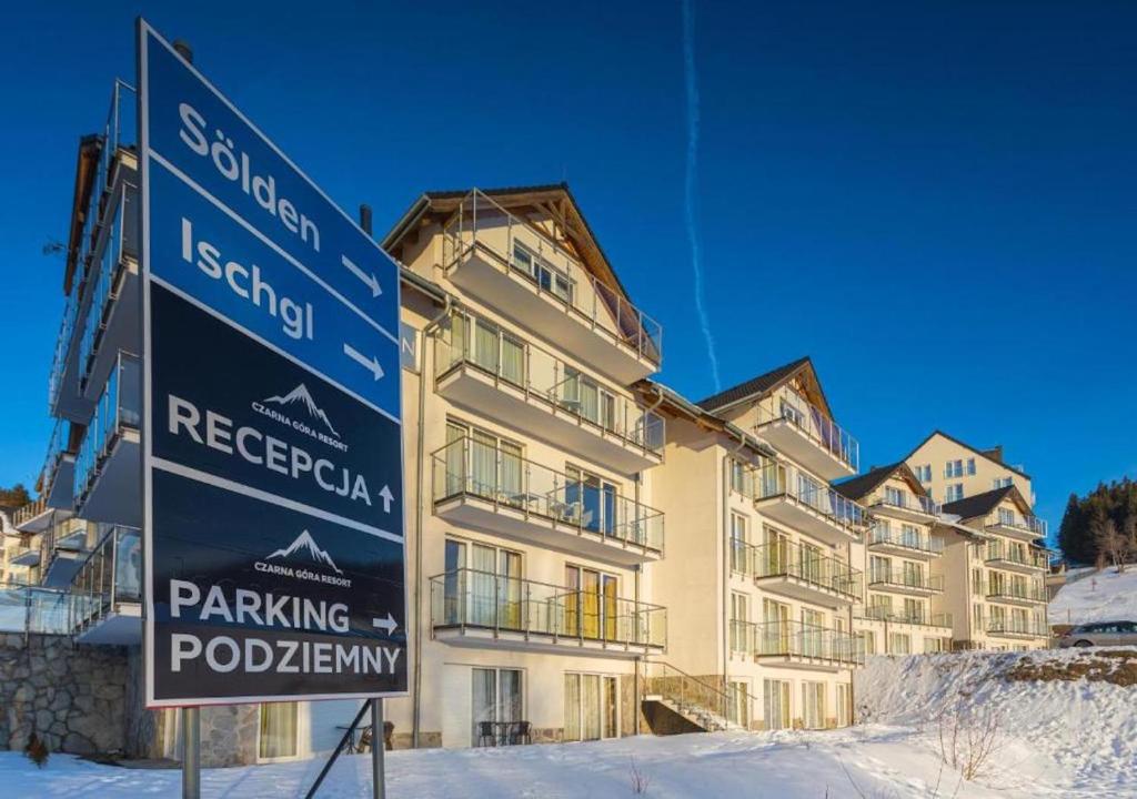 a sign in the snow in front of a building at Apartment Czarna Góra Resort ISCHGL 30, Sienna in Sienna