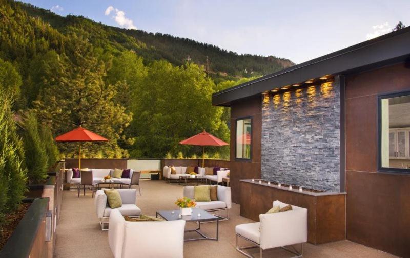 un patio avec des chaises et des tables blanches et un bâtiment dans l'établissement Luxury 2 Bedroom Downtown Aspen Vacation Rental With Access To A Heated Pool, Hot Tubs, Game Room And Spa, à Aspen