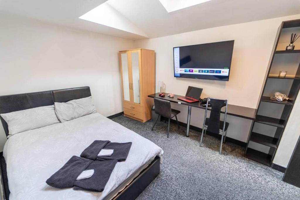 een slaapkamer met een bed, een bureau en een televisie bij Lovely Studio 10 mins from City for Short term in Birmingham