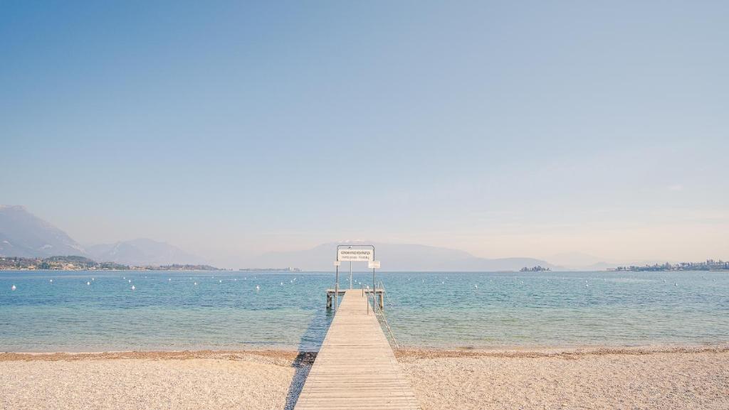a dock on a beach in the water at Il Cielo in una Stanza - Italian Homing in Manerba del Garda