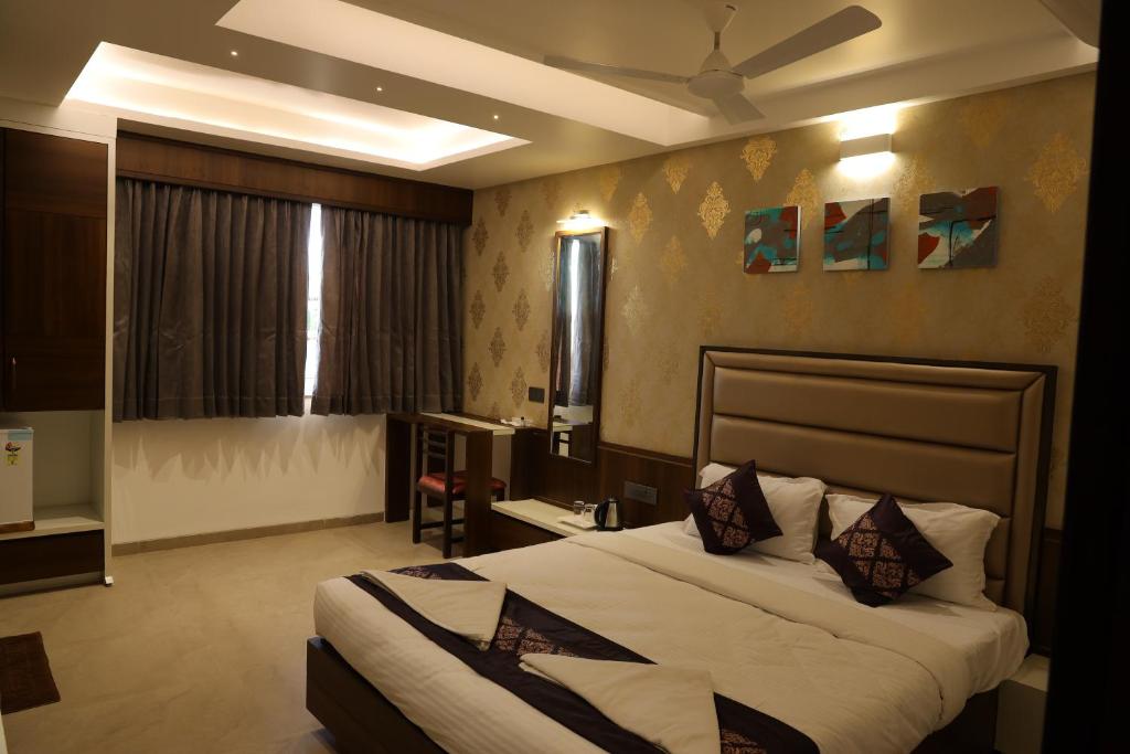 a bedroom with a large bed with a ceiling at Blisss Hotel Kolhapur in Kolhapur
