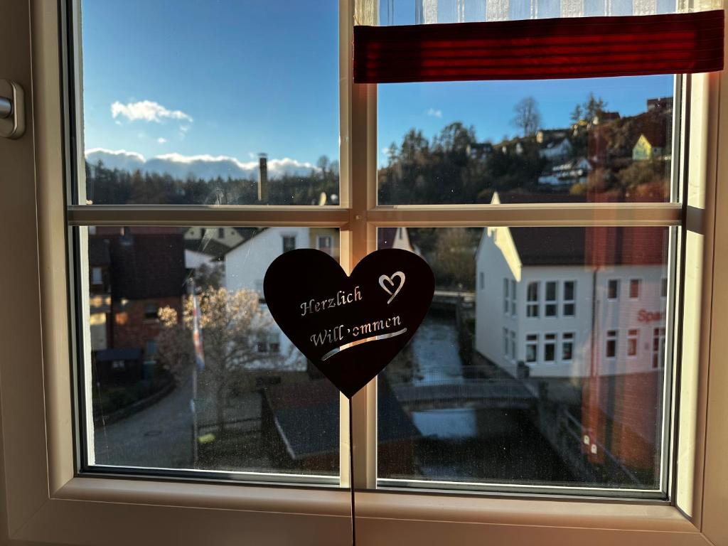 a heart shaped window with a view of a city at Gasthof Goldene Krone in Pottenstein