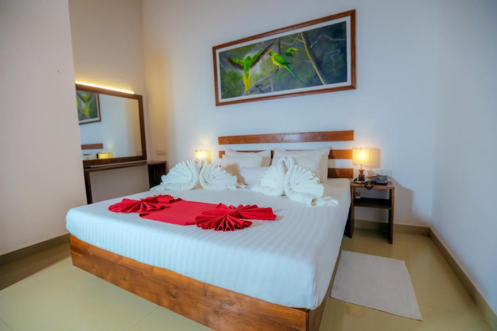 um quarto com uma grande cama branca com arcos vermelhos em Sigiri Asna Nature Resort em Sigiriya