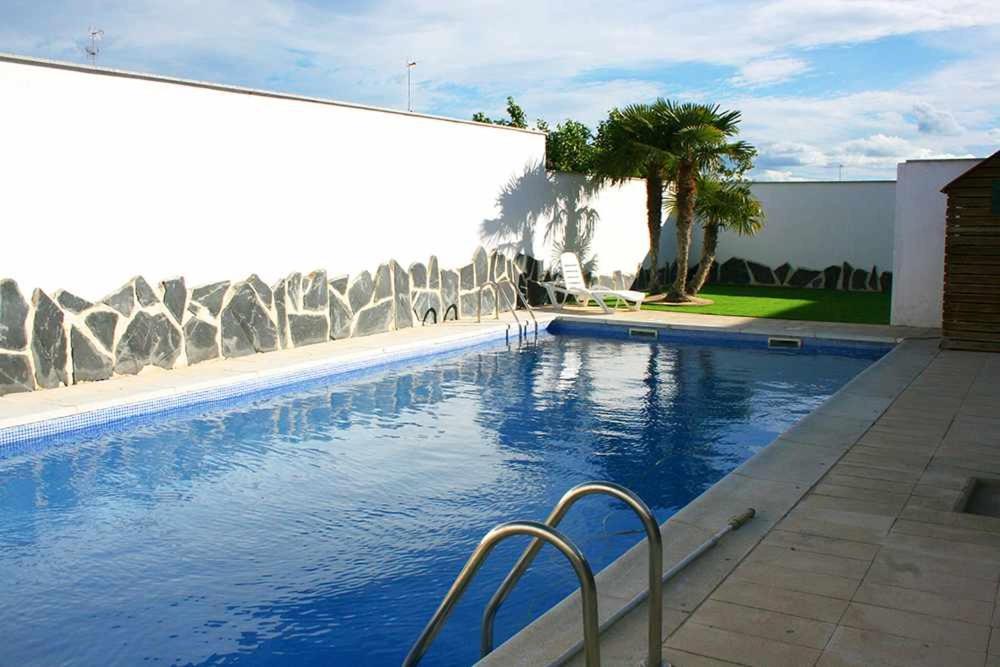 - une piscine d'eau bleue en face d'un bâtiment dans l'établissement Alojamientos Callejón del Pozo cerca Puy du Fou, à Gálvez
