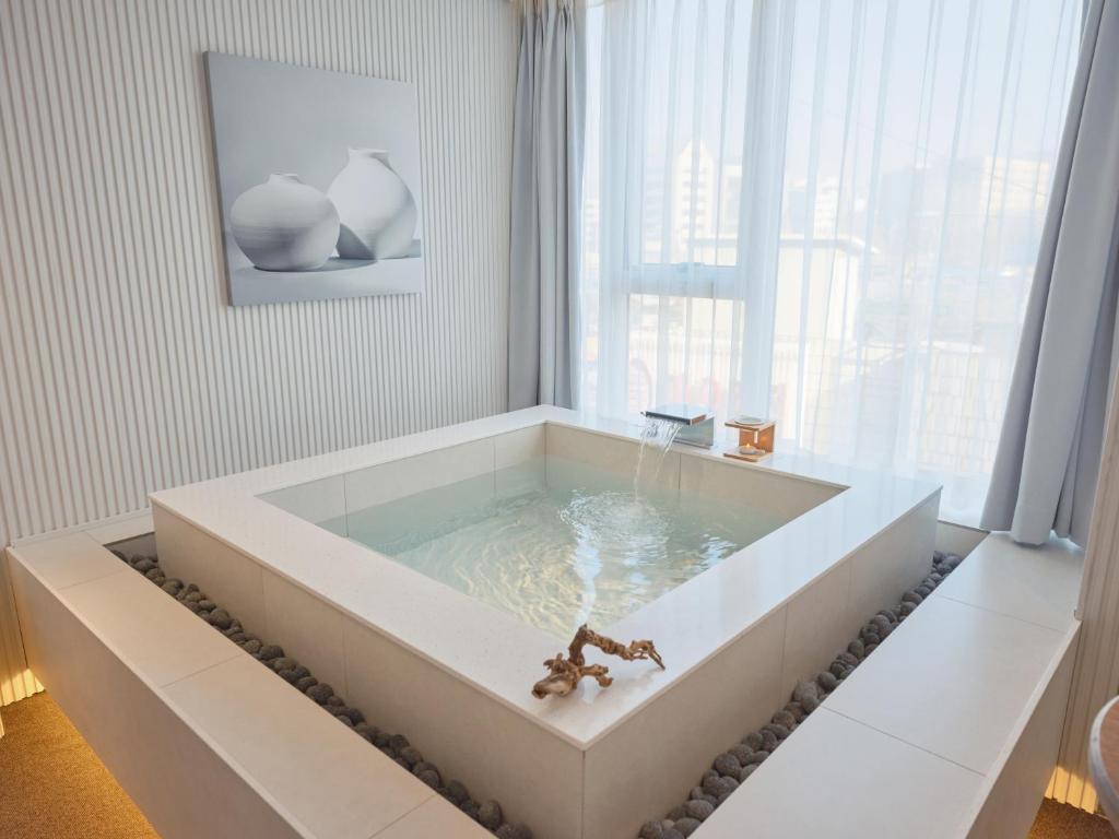 a bathroom with a bath tub with a window at The Leap Seoul Sadang in Seoul