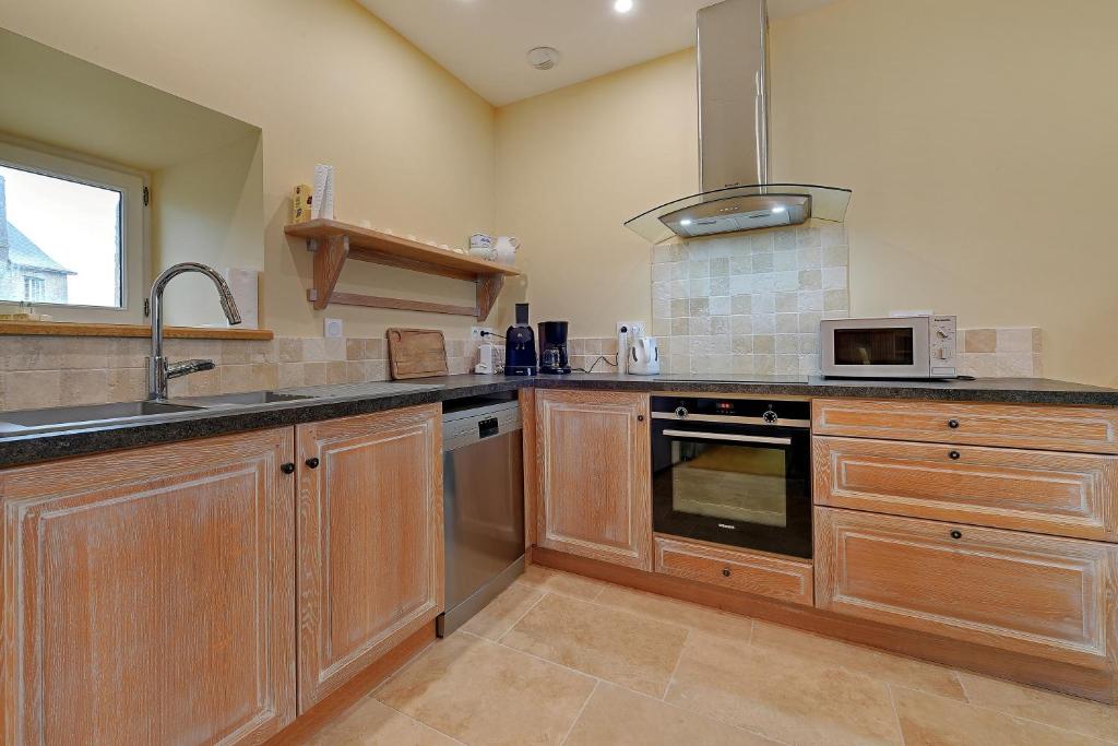 Kuchnia z drewnianymi szafkami, zlewem i kuchenką mikrofalową w obiekcie Petit Marigny - Belle maison pour 10 voyageurs w mieście Alexain
