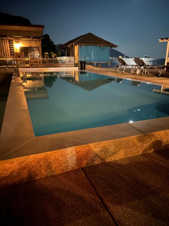 a swimming pool at night with chairs and a building at The Cosy Koh Phangan and Restaurant in Thong Sala