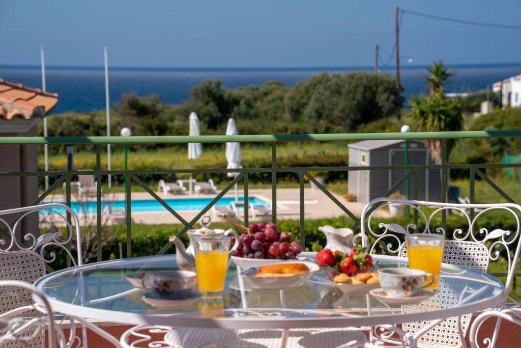 a glass table with fruit and drinks on a balcony at Monambeles Villas in Svoronata