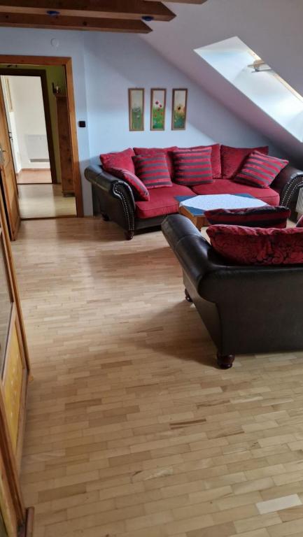ein Wohnzimmer mit einem schwarzen Sofa und roten Kissen in der Unterkunft Boutique Penzión Slovenská - Penzión Bella Sicilia in Prešov