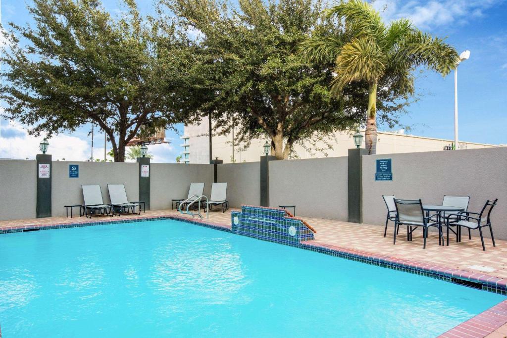 a swimming pool with chairs and tables and trees at La Quinta by Wyndham Mission at West McAllen in Mission