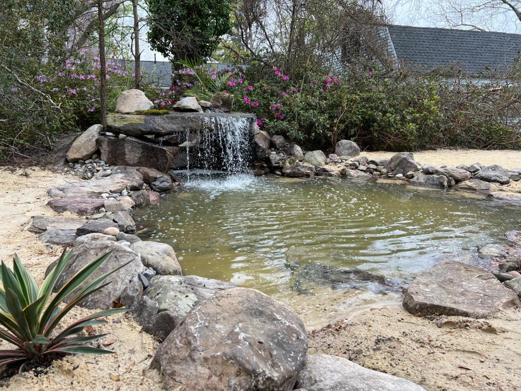 a small pond with a waterfall in a garden at Grotto Waterfall Bethel Oasis 5 bedroom House with 2 masters in Hampton