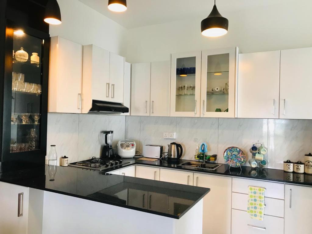 eine Küche mit weißen Schränken und einer schwarzen Arbeitsplatte in der Unterkunft Furnished homelike apartment at Mount Clifford Range,Homagama in Homagama