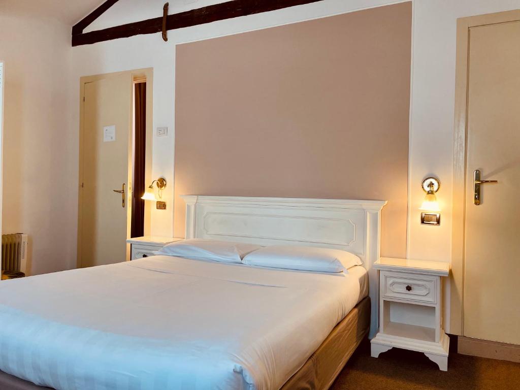 - une chambre avec un lit blanc et une tête de lit blanche dans l'établissement Alla Corte Rossa, à Venise