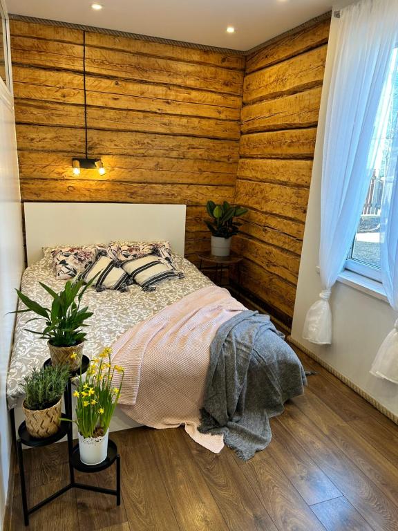Schlafzimmer mit Holzwänden und einem Bett mit Pflanzen in der Unterkunft Kreutzwaldi kodu in Võru