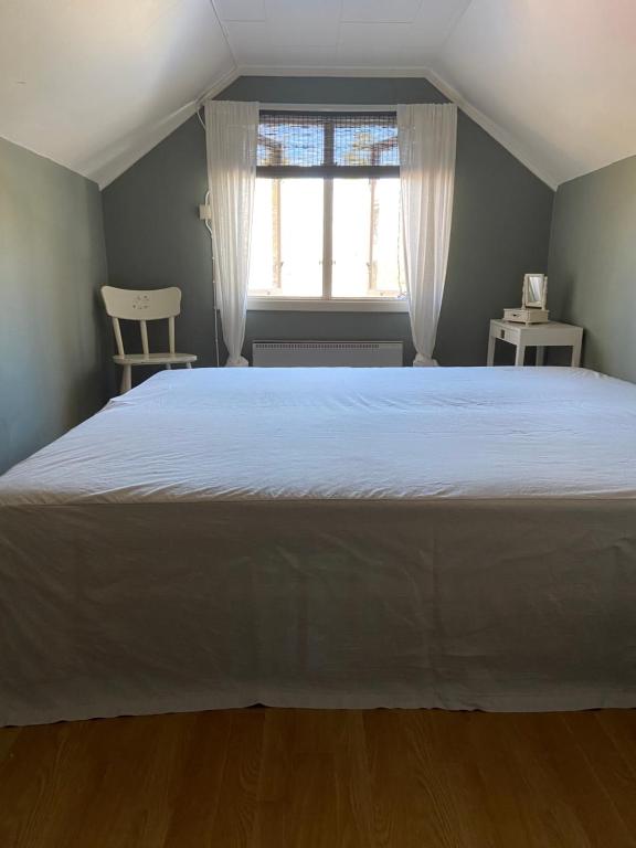 Cette chambre comprend un grand lit blanc et une fenêtre. dans l'établissement Farmhouse Marielund, à Mariannelund