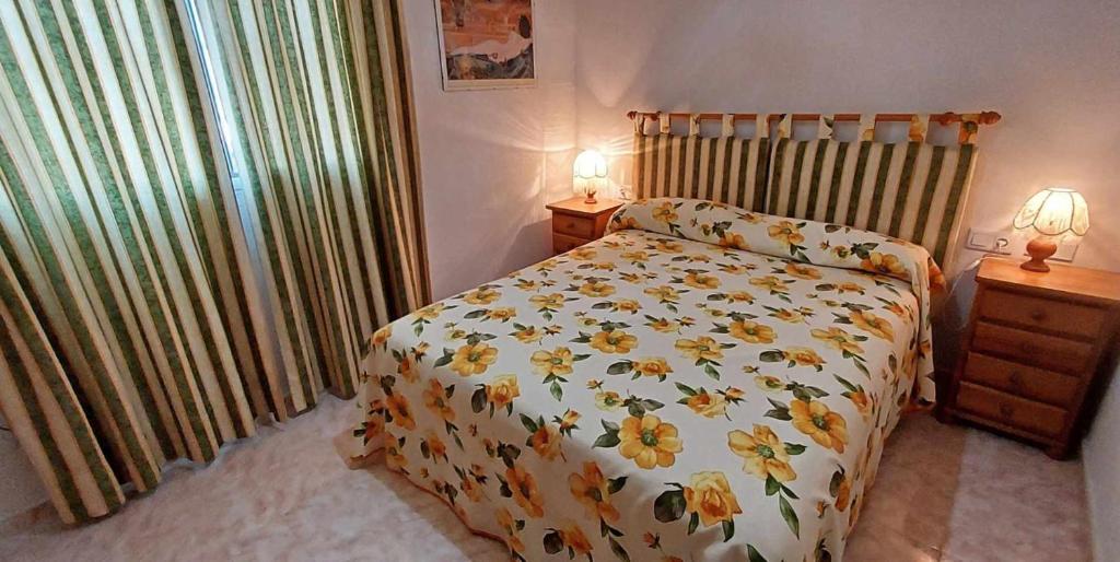 サンタ・ポラにあるApartamento LIDIAのベッドルーム1室(黄色い花の掛け布団付きのベッド1台付)
