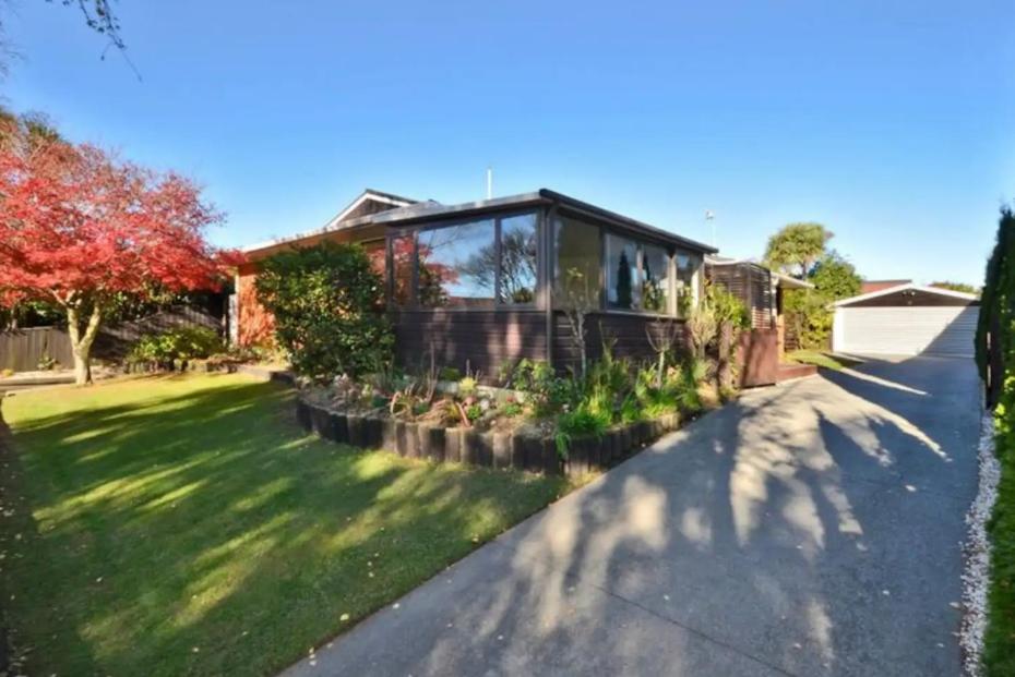 een huis met een tuin met groen gras bij Highland Place Avonhead in Christchurch