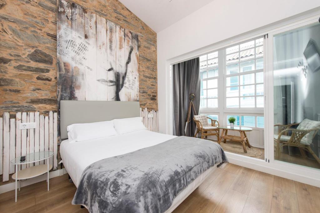 a bedroom with a large bed and a brick wall at Hotel A Falúa in Puentedeume