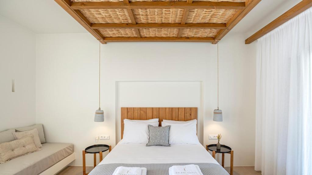 a bedroom with a white bed and a couch at Kalami Suites in Livadi