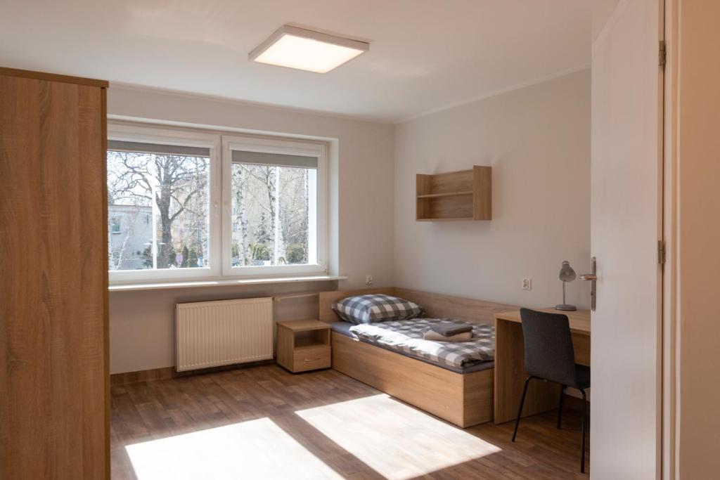 a room with a bed and a desk and a window at Dom Studencki Komenik in Leszno