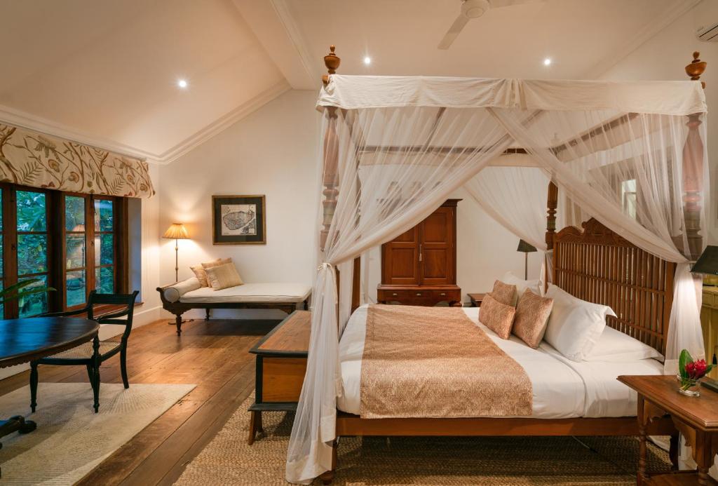 een slaapkamer met een hemelbed en een bureau bij Taru Villas Rampart Street - Galle Fort in Galle