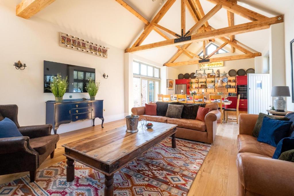 a living room with wooden ceilings and a table at Alde Bay Farm - Barn Owl Sanctuary in Aldeburgh