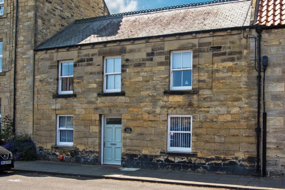 an old brick house with a blue door at Clara's Cottage in Warkworth