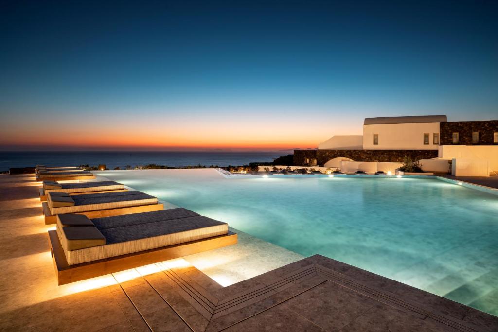 a swimming pool with lounge chairs in a resort at Santo Pure Oia Suites & Villas in Oia