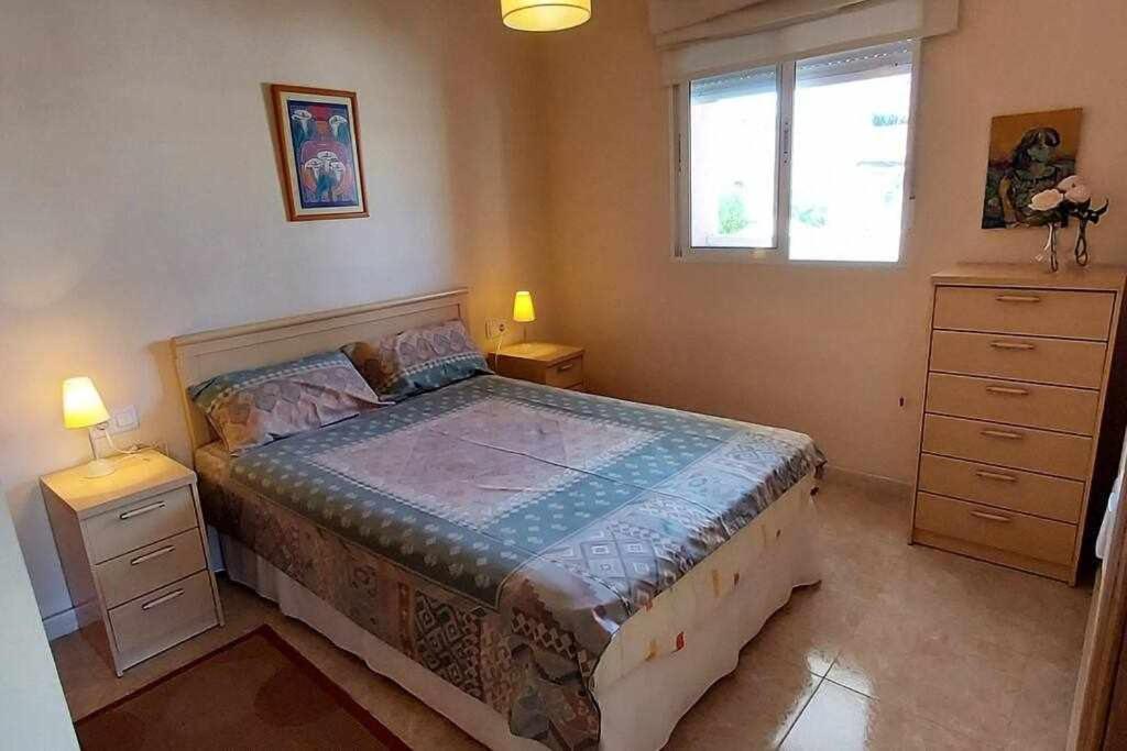 ein Schlafzimmer mit einem Bett, zwei Nachttischen und einem Fenster in der Unterkunft Apartamento Salamanca 4 in Santa Pola