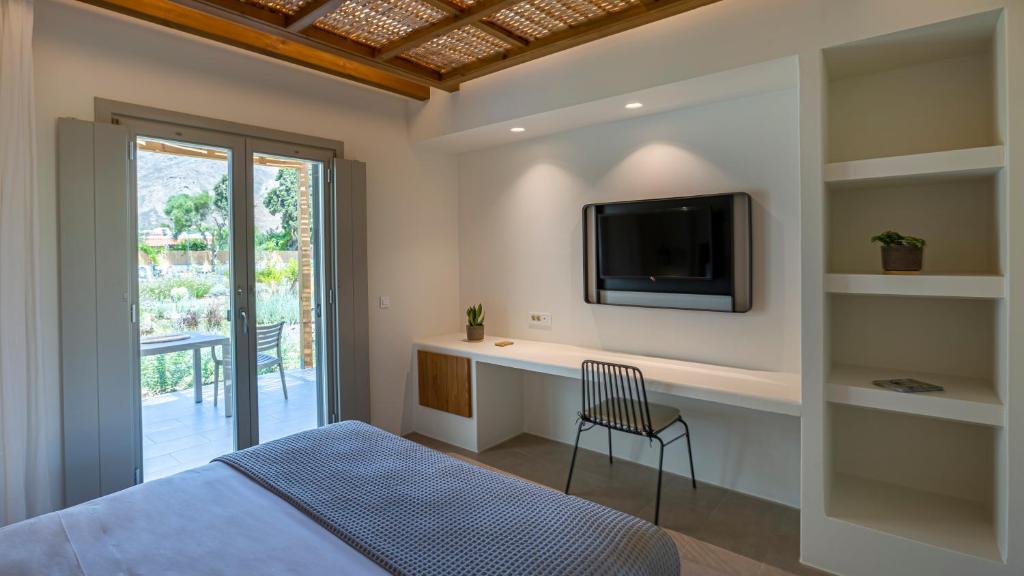 a bedroom with a bed and a tv on a wall at Kalami Suites in Livadi