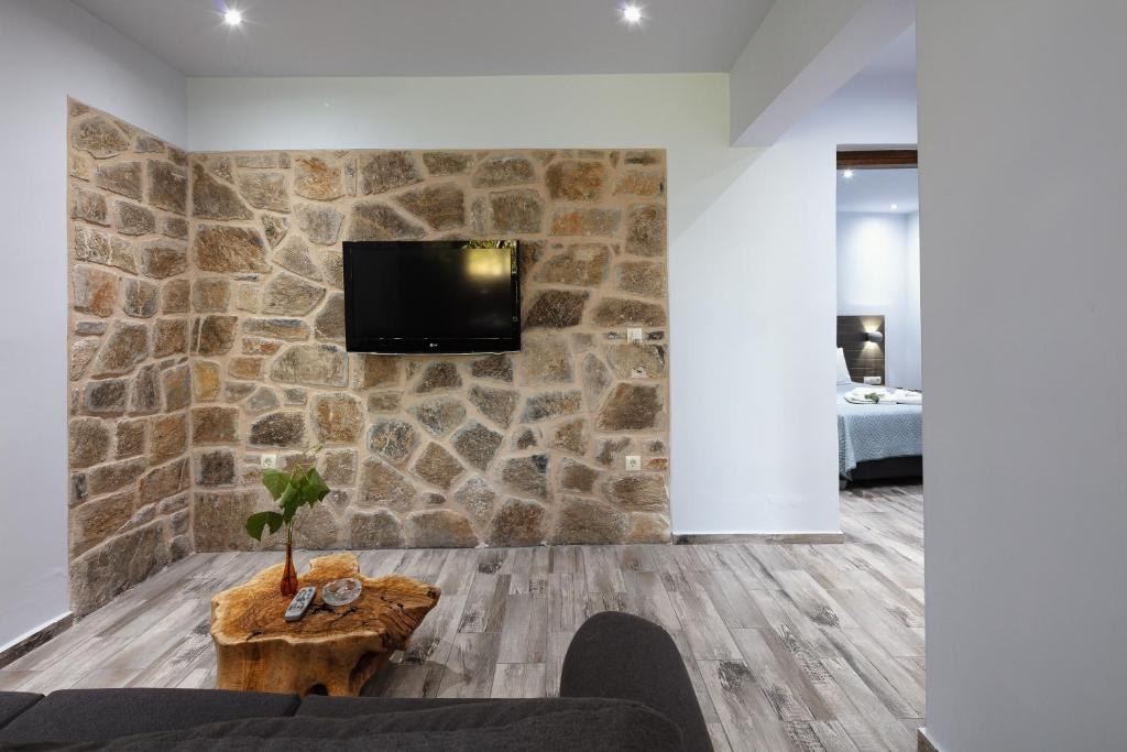 uma sala de estar com televisão numa parede de pedra em Green View Studios & Apartments em Dhamnóni