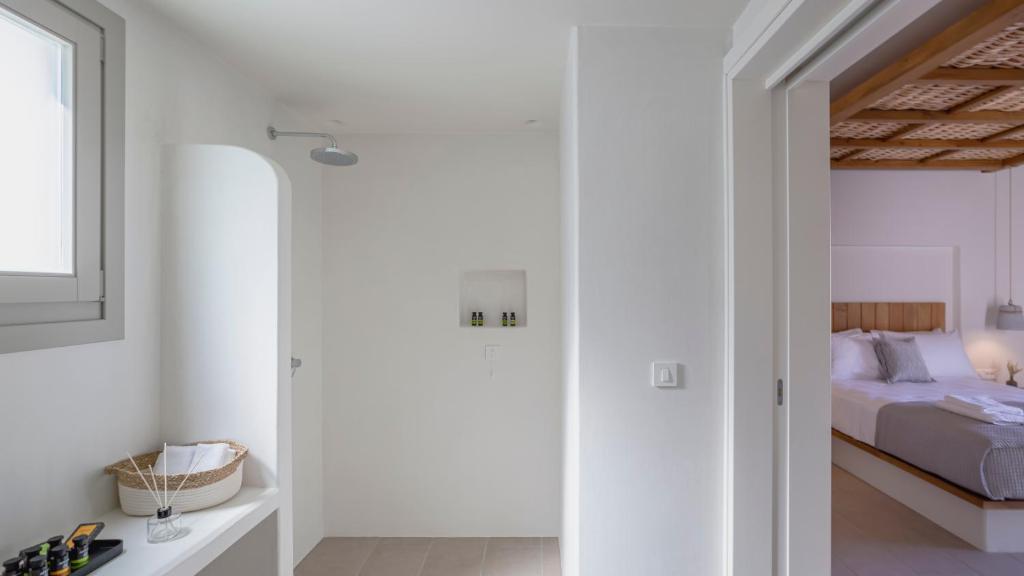 a white bedroom with a bed and a window at Kalami Suites in Livadi