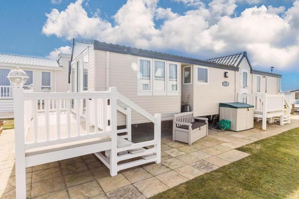 a white house with a staircase in a yard at Luxury Caravan For Hire At Hopton Holiday Park With Full Sea Views Ref 80010h in Great Yarmouth