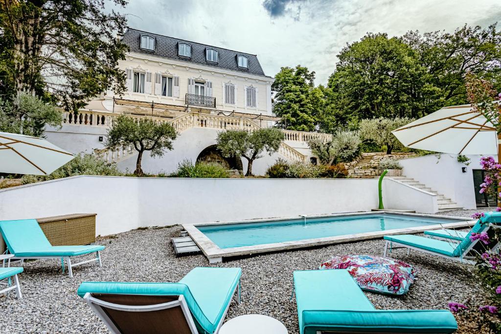 a pool with chairs and umbrellas in front of a building at Manoir d&#39;Amaury - Chambres d&#39;hôtes in Gréoux-les-Bains
