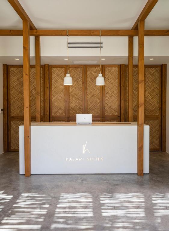 a white reception desk in a room with wood columns at Kalami Suites in Livadi