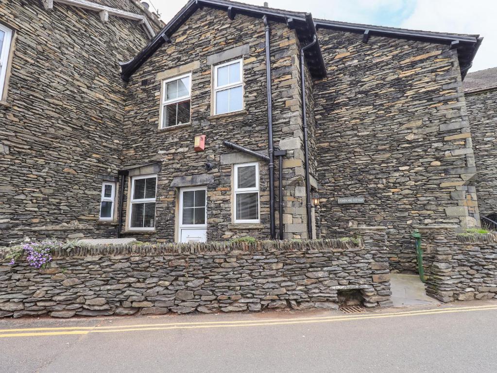 an old stone house with a stone wall at Gildabrook Cottage in Bowness-on-Windermere