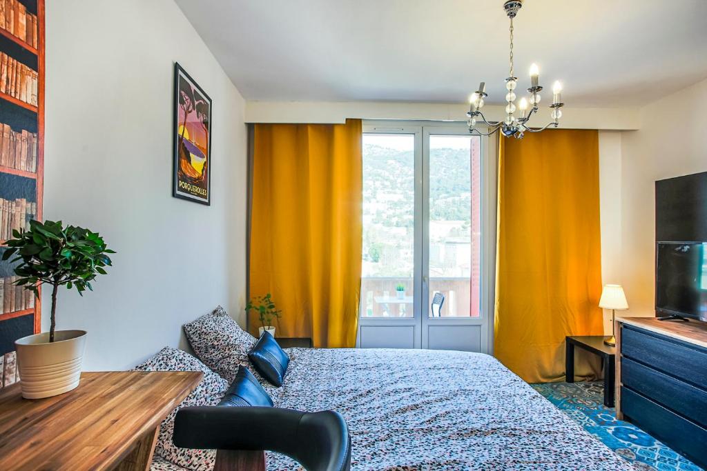 Schlafzimmer mit einem Bett und einem Fenster mit gelben Vorhängen in der Unterkunft #4 Toulon CENTRE, BALCON, VUE SUR CORNICHE, LUMINEUX, AU CALME, STATIONNEMENT FACILE & GRATUIT in Toulon