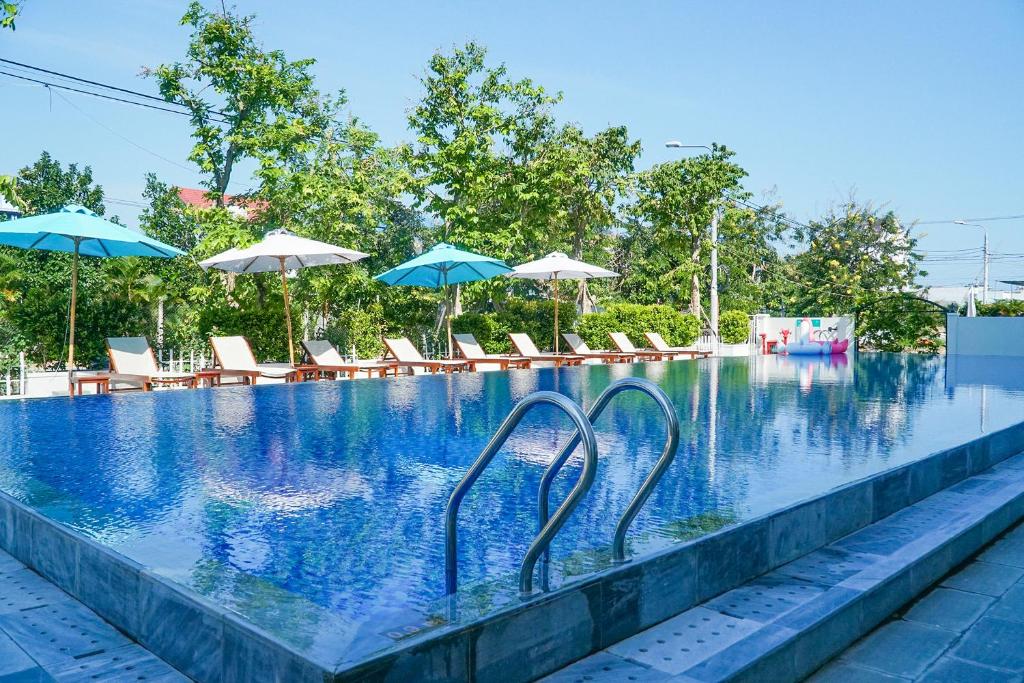 a swimming pool with chairs and umbrellas at Hoi An Town Home Resort in Hoi An