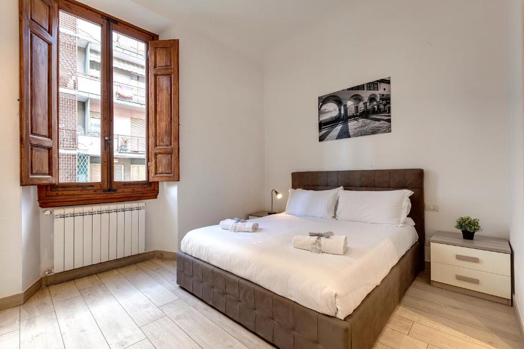 a bedroom with a large bed and a window at Mamo Florence - Baldovini Apartment in Florence