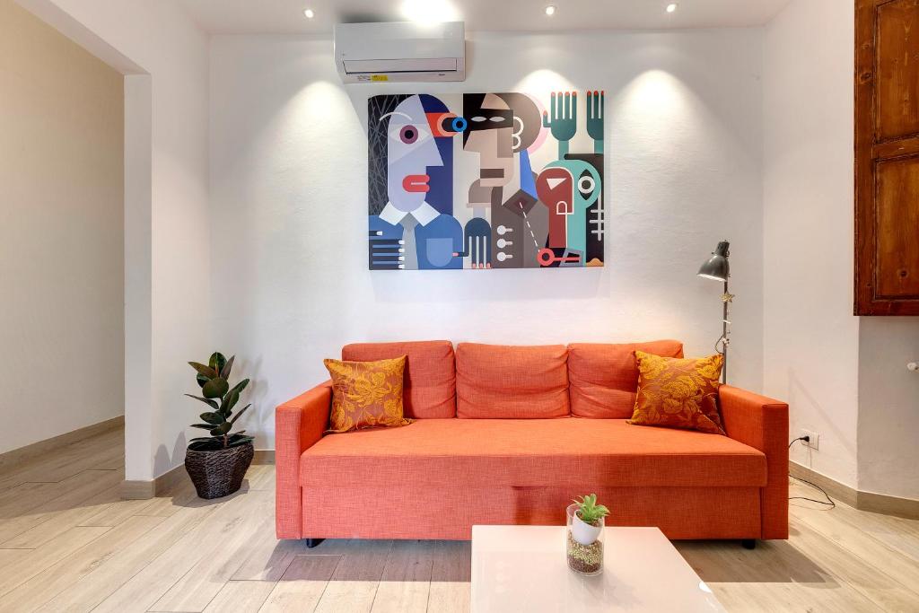 un sofá naranja en una sala de estar con una pintura en Baldovini Apartment by Mamo Florence, en Florencia